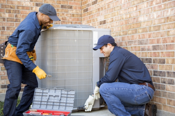 Two technicians installation an HVAC unit